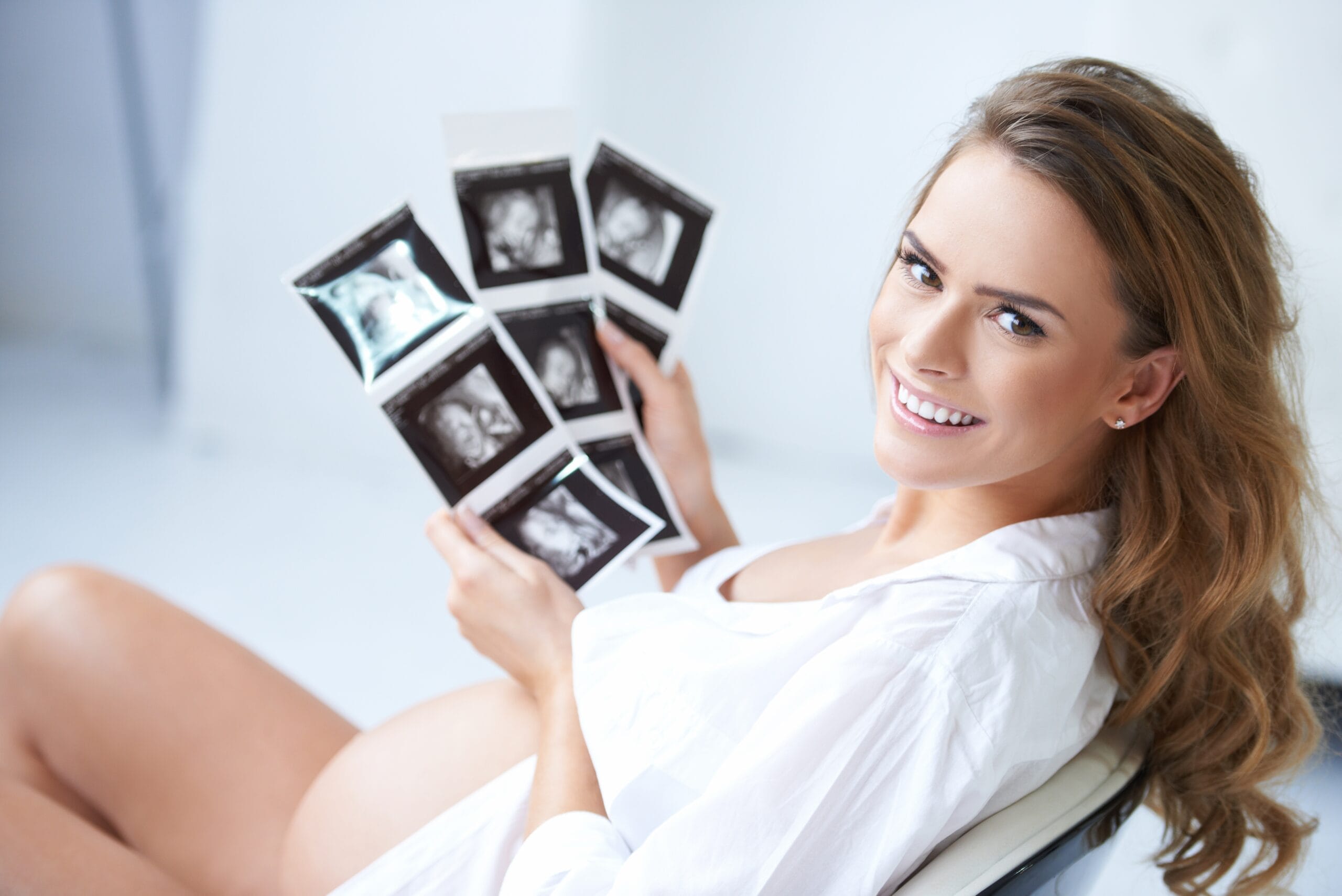 kobieta trzymająca zdjęcia USG zrobione w trakcie badań prenatalnych